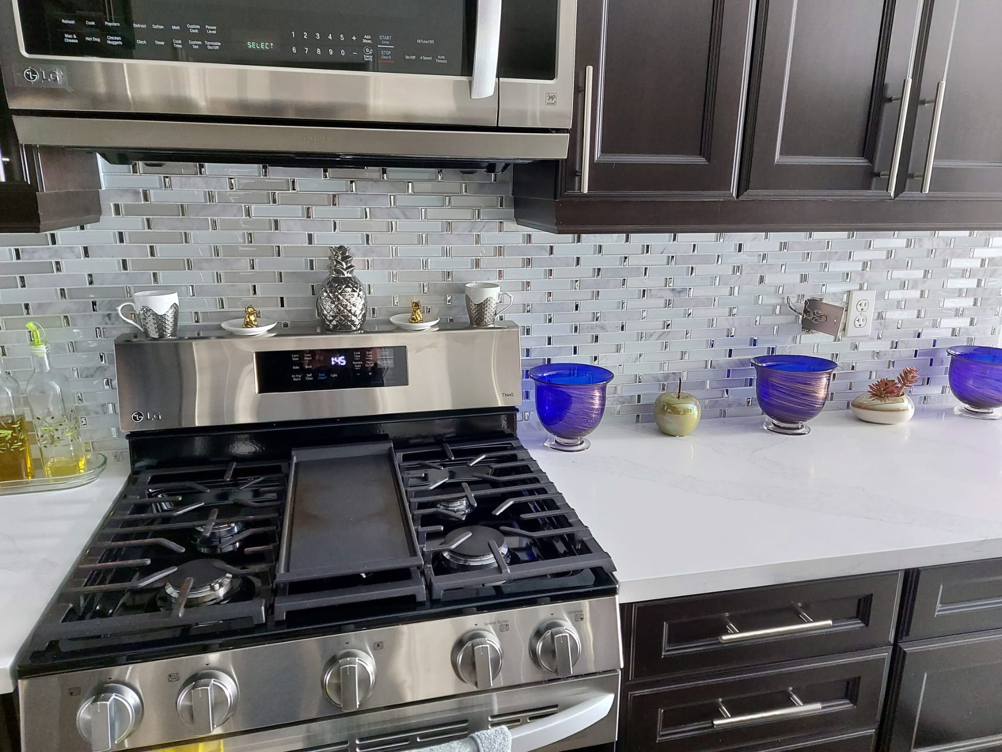 Glass mosaic kitchen backsplash above stainless gas range